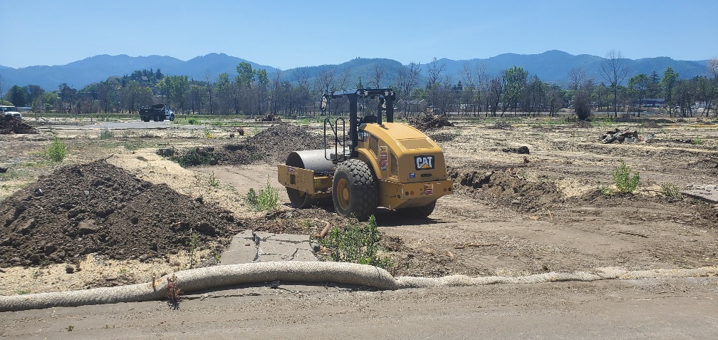 A bulldozer in a dirt field with mountains in the background.