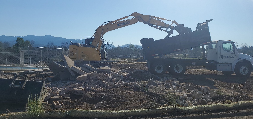An excavator is working on a pile of rubble.