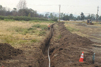 A construction crew is working on a pipe in a field.