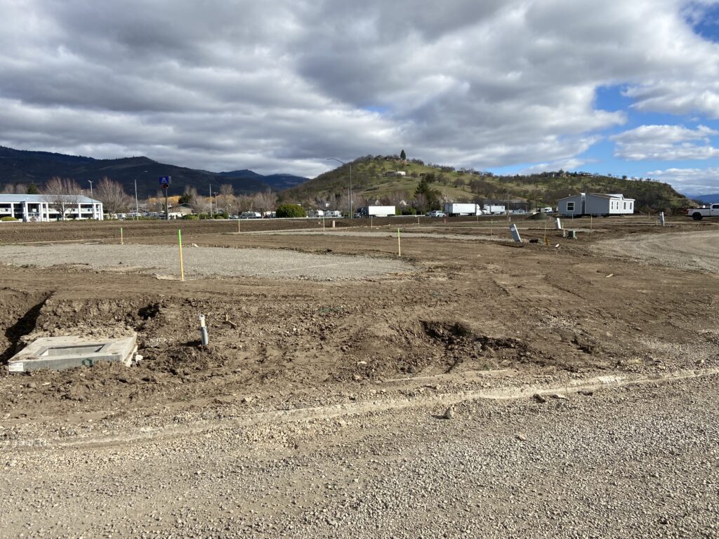 A construction site with a dirt road and mountains in the background.