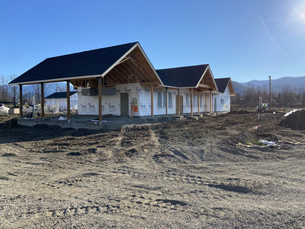 A house under construction with mountains in the background.