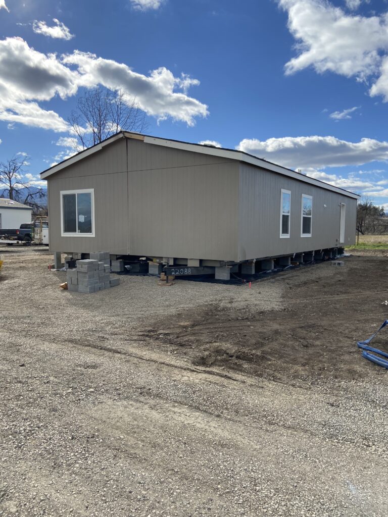 A mobile home is being built in a dirt lot.