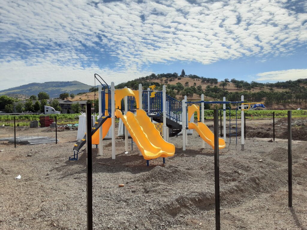 A playground with a yellow slide and a mountain in the background.