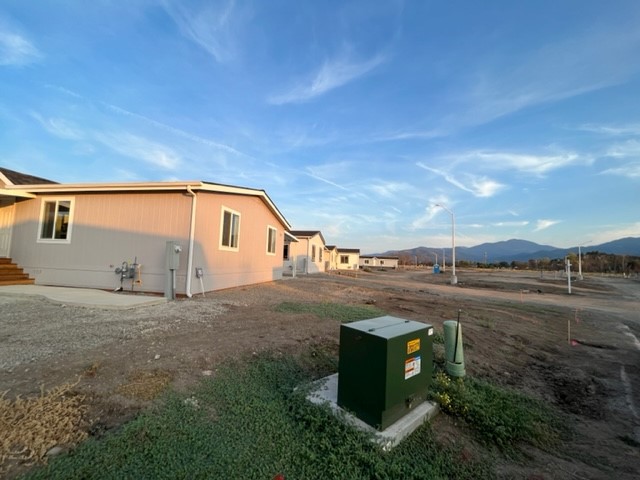 A mobile home on a dirt lot with mountains in the background.