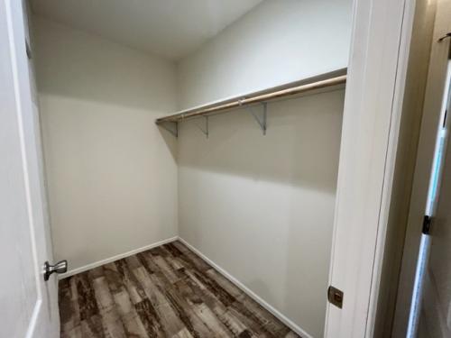 A closet with a wooden floor and a wooden shelf.
