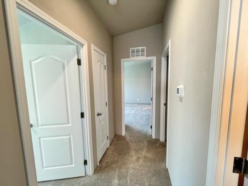 A hallway in a home with white doors and carpet.
