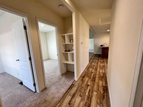 A hallway in a room with hardwood floors.