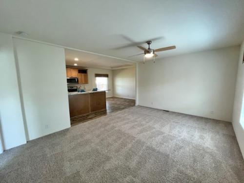 An empty living room with carpet and ceiling fan.