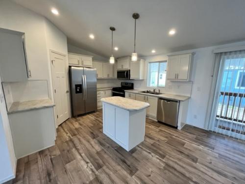 An empty kitchen with wood floors and stainless steel appliances.