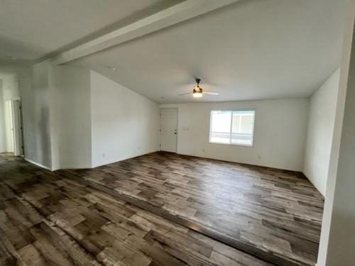 An empty room with wood floors and a ceiling fan.