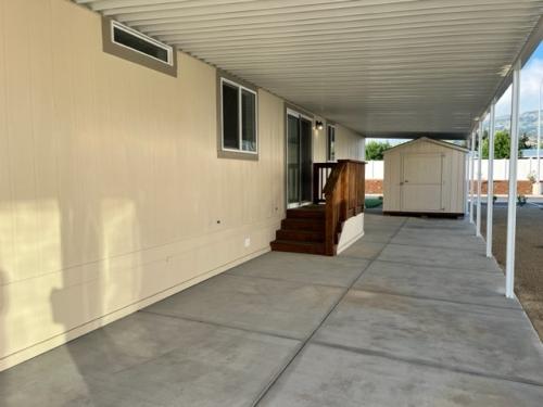 The outside of a mobile home with a door leading to a patio.