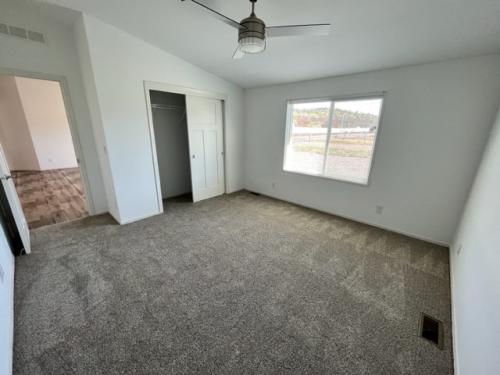 An empty room with carpet and a ceiling fan.