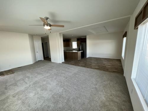 An empty living room with a ceiling fan.