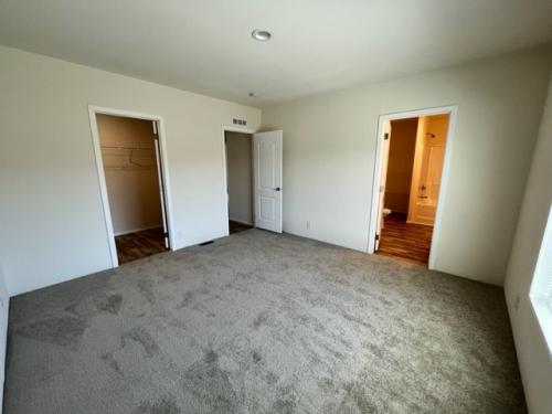 An empty room with carpet and closets.