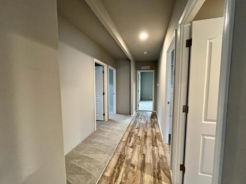 A hallway with wood floors and white walls.