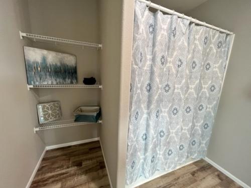 A bathroom with a shower curtain and shelves.